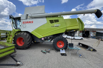Moissonneuse-batteuse Claas Tucano 580 avec équipement d'équilibrage du rotor comprenant un ordinateur portable, des capteurs et des câbles pour l'analyse des vibrations.